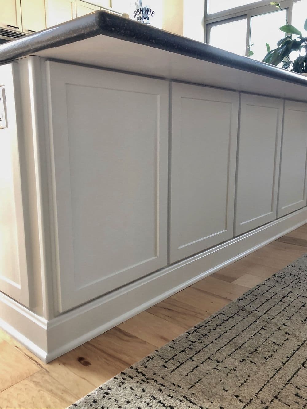 Modern kitchen island with white cabinetry and dark granite countertop, showcasing a clean design.