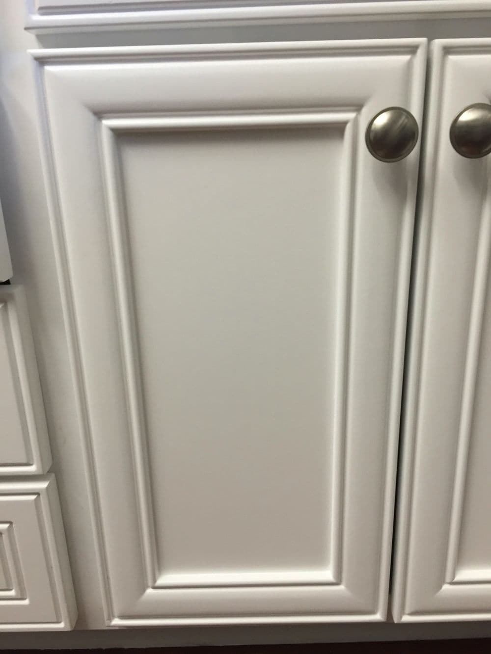 White bathroom cabinetry with brushed nickel hardware and a countertop sink.