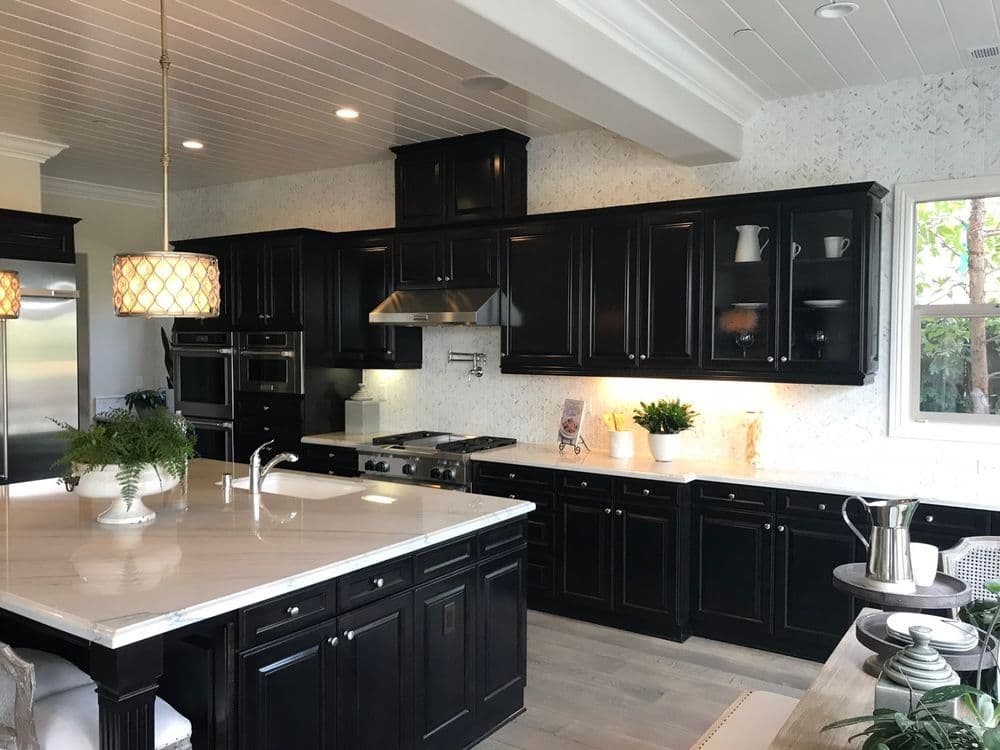 Modern kitchen featuring black cabinets, white countertops, and stylish pendant lighting.
