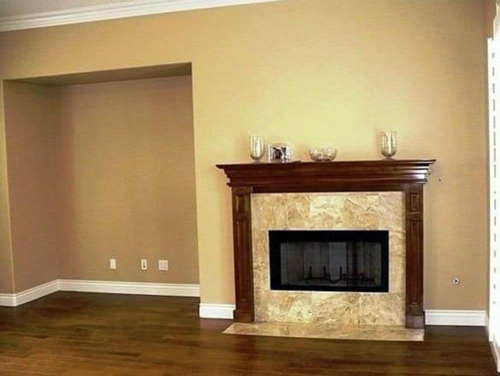 Living room with a wooden fireplace and beige walls, showcasing a cozy, minimalist design.