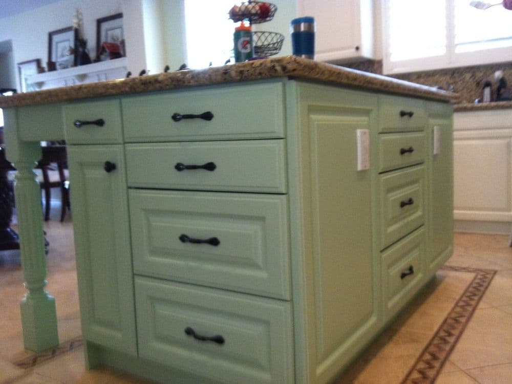 Mint green kitchen island with granite countertop and multiple storage drawers.
