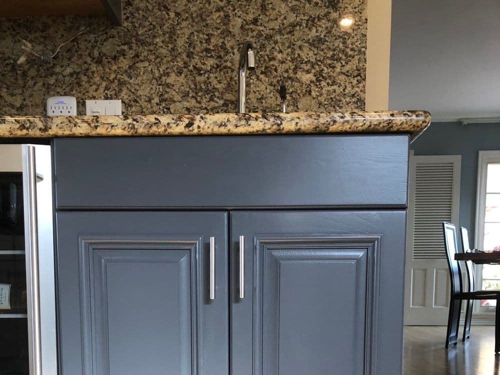 Gray kitchen cabinet with granite countertop and modern faucet in contemporary kitchen design.