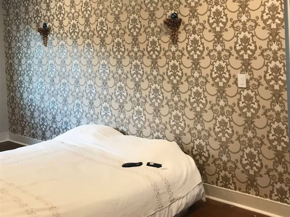 Cozy bedroom with patterned wallpaper and a neatly made bed.